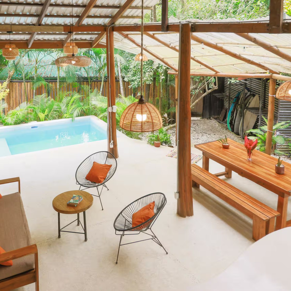 The covered terrace beside the pool, with hanging lamps and low chairs