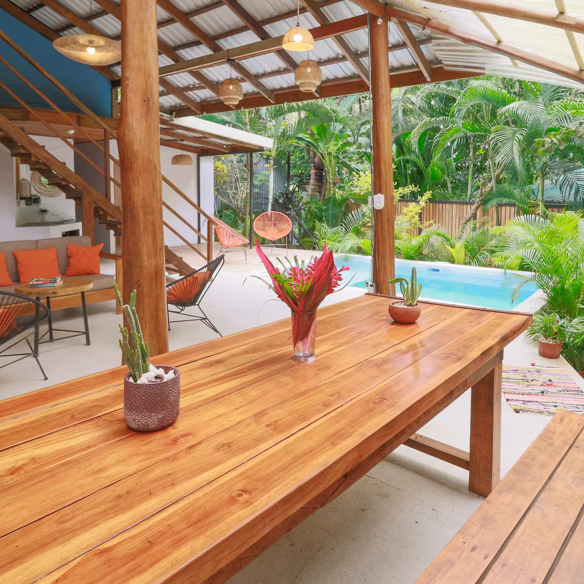 The long dining table under the open-air roof, with the pool beyond