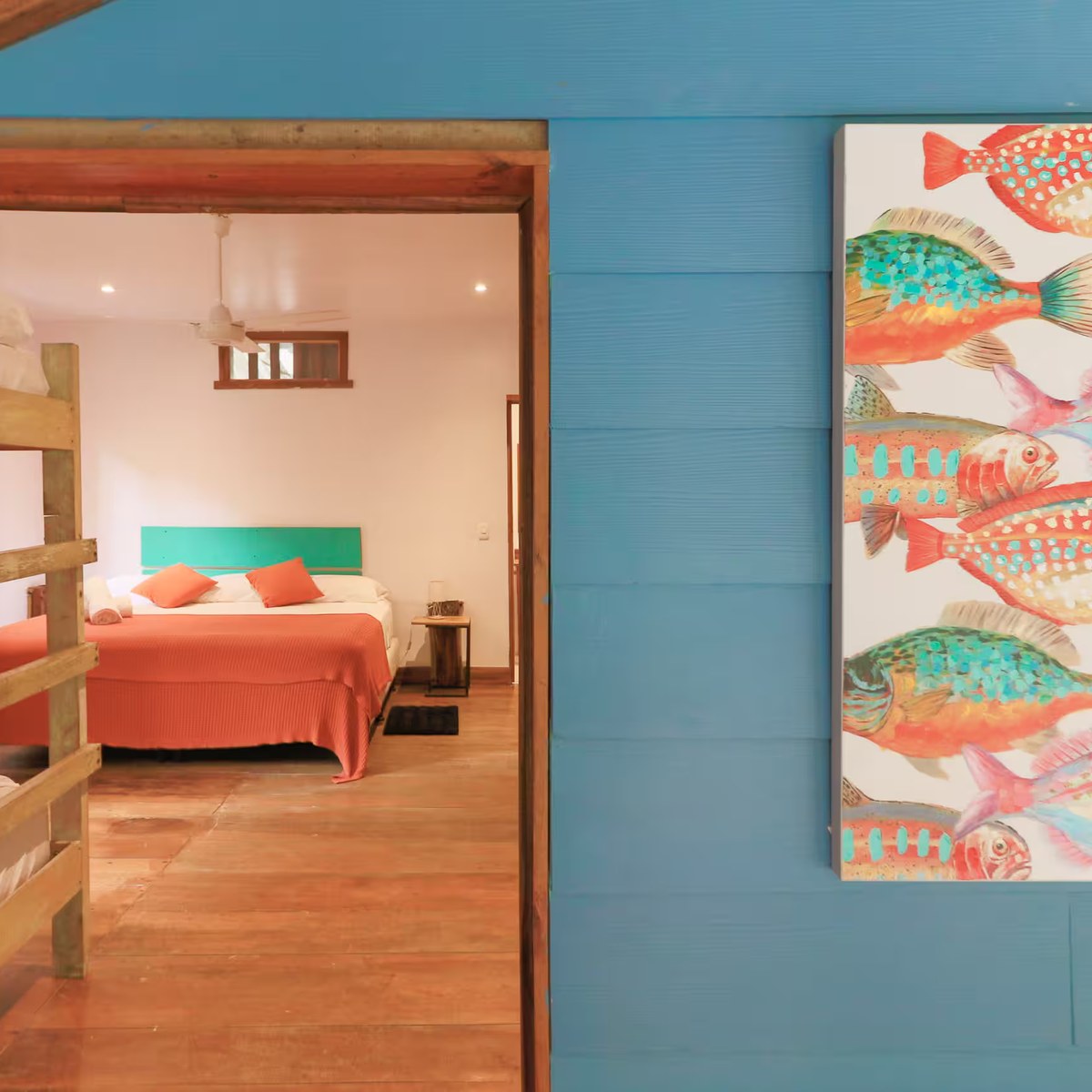 A bedroom seen through its doorway, beside a painted fish mural